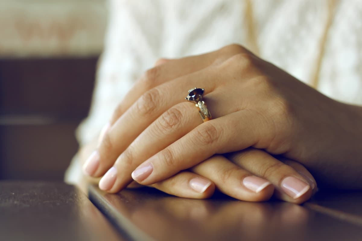 Person wearing silver-colored ring with black gemstone - symbolizing reflection and healing